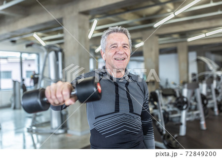 Losing weight and gainiong strength by a dumbell training performed by older man in the fitness center 72849200