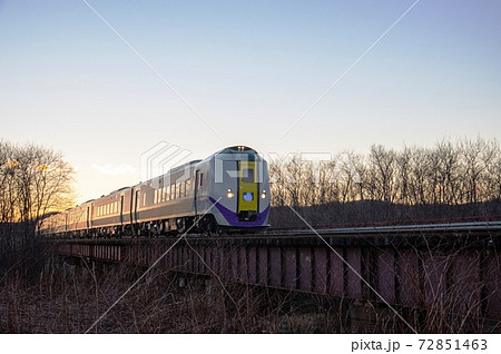 夕日の中を疾走する特急おおぞらの写真素材
