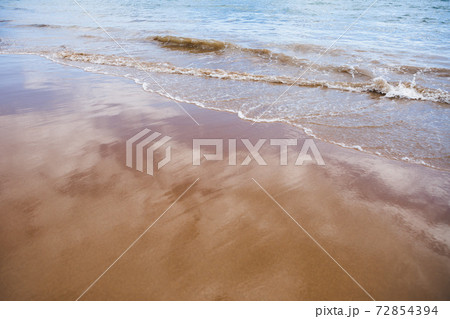 wet sand beach background and sea water 72854394