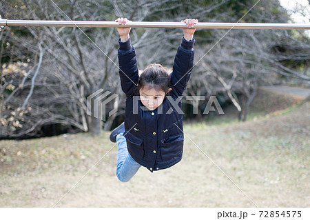 鉄棒で遊ぶ女の子の写真素材