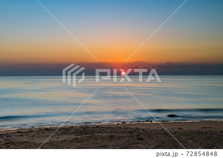 Sunrise over calm sea. Dawn over horizon, ocean, water. Clear sky. The Sun rises over the beach, coast, shore. 72854848