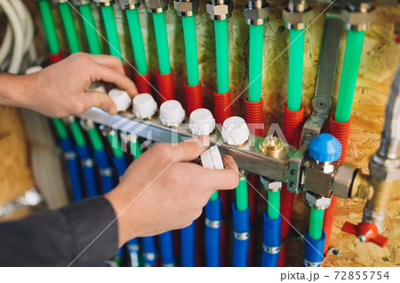 underfloor heating manifold collector with pipes, hands balancing temperature 72855754