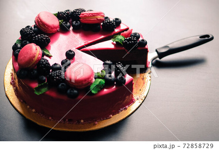 Delicious cake with fresh strawberries, raspberries, blueberry, currants. cut piece of cake and blade on wooden background. 72858729