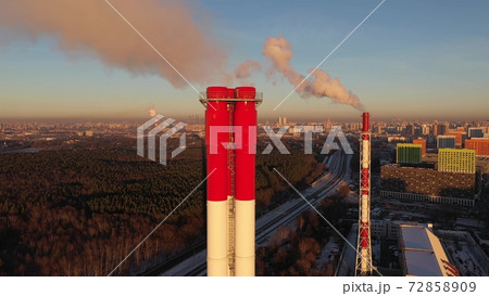 Aerial shot of the skyline of Moscow behind red and white industrial smoke stacks in winter evening, Russia Aerial shot of the skyline of Moscow behind red and white industrial smoke stacks in winter evening, Russia 72858909