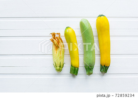 Green and yellow zucchini. Fresh vegetables. On a white wooden table. View from above. 72859234
