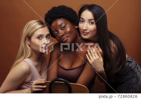 young pretty asian, caucasian, afro woman posing cheerful together on brown background, lifestyle diverse nationality people concept young pretty asian, caucasian, afro woman posing cheerful together on brown background, lifestyle diverse nationality people concept 72860826