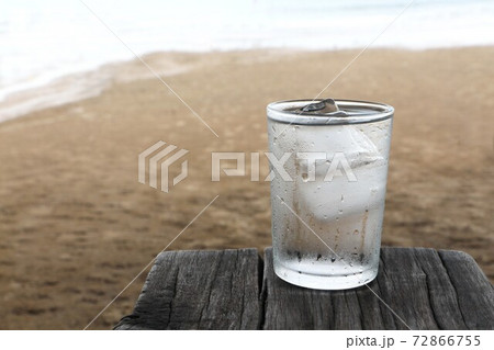 Drink water with cold ice in glass of water on old wooden plank on the beach. Drink water with cold ice in glass of water on old wooden plank on the beach. 72866755