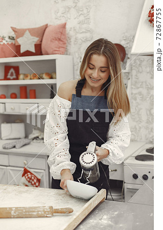 Smiling blonde woman preparing a cake in a kitchen Smiling blonde woman preparing a cake in a kitchen 72867755