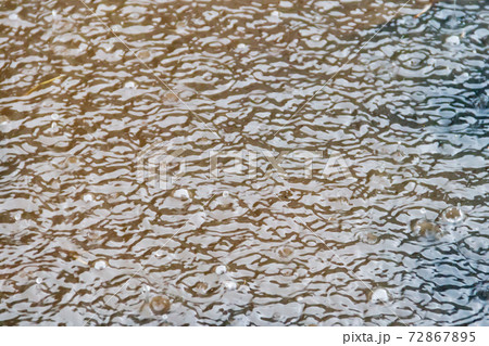 Puddle of water with splashing raindrops during a downpour 72867895