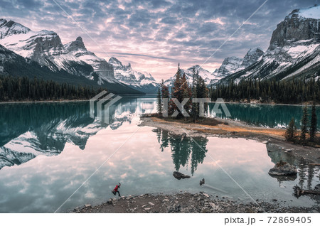 Man traveler jumping on lakeside in Spirit Island on Maligne Lake at Jasper National Park Man traveler jumping on lakeside in Spirit Island on Maligne Lake at Jasper National Park 72869405