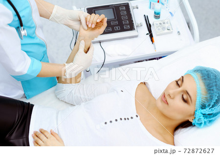 Female doctor and young woman patient in hospital. Physicians examine girl pulse lying at the bed, view from above. Medical help and insurance in health care, best treatment and medicine concept Female doctor and young woman patient in hospital. Physicians examine girl pulse lying at the bed, view from above. Medical help and insurance in health care, best treatment and medicine concept 72872627
