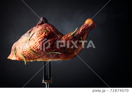 Smoked chicken thigh on a fork sprinkled with rosemary. Smoked chicken thigh on a fork sprinkled with rosemary. 72874070
