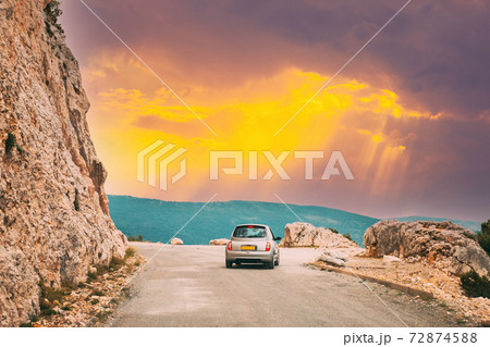 Verdon, France. Small car on road on background of French mountain nature landscape the Gorges Du Verdon in France. Altered Sunset Sky Verdon, France. Small car on road on background of French mountain nature landscape the Gorges Du Verdon in France. Altered Sunset Sky 72874588