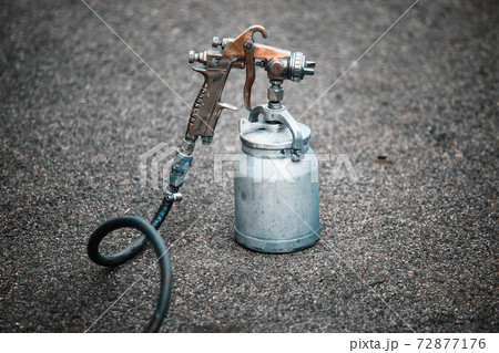 An old spray gun stands on the asphalt. Theme of industrial painting.  72877176
