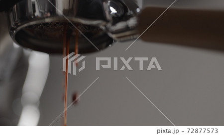 low angle bad shot of espresso extraction from naked portafilter into white cup low angle bad shot of espresso extraction from naked portafilter into white cup 72877573