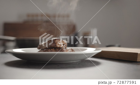 Man hand put cooked steak on white plate for resting before serving 72877591