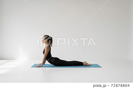 Young woman practicing yoga, lying and stretching in Cobra pose, doing Bhujangasana exercise. Attractive girl in black sportswear. Beautiful sporty fit yogini woman practices yoga asana bhujangasana. Young woman practicing yoga, lying and stretching in Cobra pose, doing Bhujangasana exercise. Attractive girl in black sportswear. Beautiful sporty fit yogini woman practices yoga asana bhujangasana. 72878804