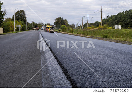 Asphalt road roller with heavy vibration roller compactor press new hot asphalt on the roadway on a road construction site. Heavy Vibration roller at asphalt pavement working. Repairing. Asphalt road roller with heavy vibration roller compactor press new hot asphalt on the roadway on a road construction site. Heavy Vibration roller at asphalt pavement working. Repairing. 72879106