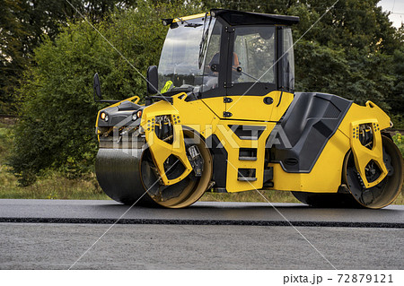 Asphalt road roller with heavy vibration roller compactor press new hot asphalt on the roadway on a road construction site. Heavy Vibration roller at asphalt pavement working. Repairing. Asphalt road roller with heavy vibration roller compactor press new hot asphalt on the roadway on a road construction site. Heavy Vibration roller at asphalt pavement working. Repairing. 72879121