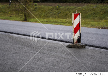 A large layer of fresh hot asphalt. Layer of asphalt raw material in a shallow depth of field. Rollers rollin fresh hot asphalt on the new road. Road construction. Construction of a new road. A large layer of fresh hot asphalt. Layer of asphalt raw material in a shallow depth of field. Rollers rollin fresh hot asphalt on the new road. Road construction. Construction of a new road. 72879126