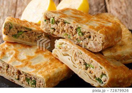 Saudi Street Food Mutabbaq with meat, egg and green onion closeup in the board. Horizontal Saudi Street Food Mutabbaq with meat, egg and green onion closeup in the board. Horizontal 72879926