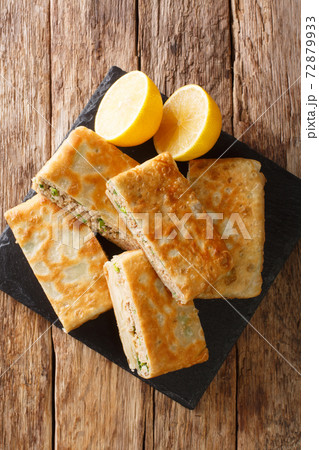 Murtabak is a stuffed pancake or pan-fried bread with meat, egg and green onion closeup in the board. vertical top view Murtabak is a stuffed pancake or pan-fried bread with meat, egg and green onion closeup in the board. vertical top view 72879933