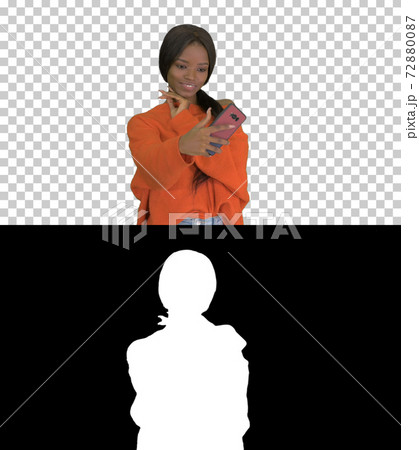 Smiling african american woman in bright jumper taking selfie an 72880087