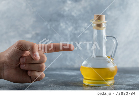 Man point finger to bottle of oil 72880734