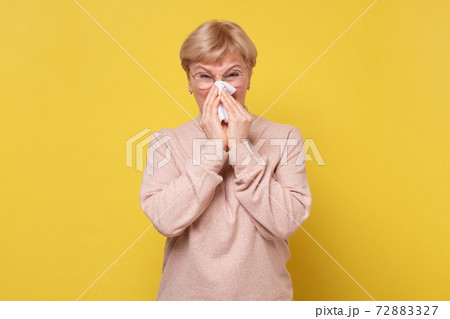 Portrait of an attractive woman sneezing while standing against a white background Portrait of an attractive woman sneezing while standing against a white background 72883327