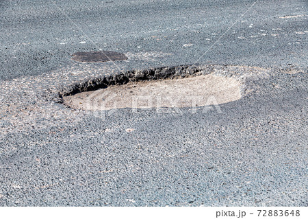 Large pothole an example of poor road maintenance Large pothole an example of poor road maintenance 72883648