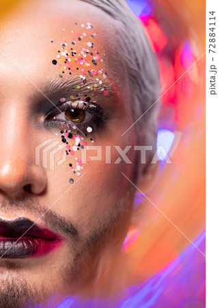 Half of face of young actor with stage makeup and white hair looking at you 72884114