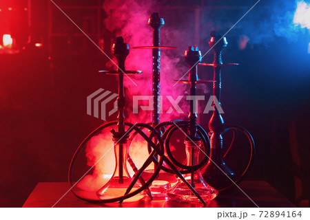 group of hookahs with shisha coals in bowls on a red and blue background with smoke group of hookahs with shisha coals in bowls on a red and blue background with smoke 72894164