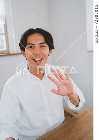 こちらに向かって手を振る30代男性の写真素材