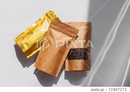 Brown kraft paper pouch bags with coffee beans top view with shadow isolated on white background.Food packaging flat lay Brown kraft paper pouch bags with coffee beans top view with shadow isolated on white background.Food packaging flat lay 72897273