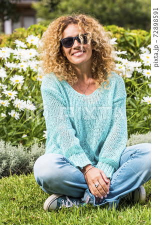 Happy and cheerful beautiful caucasian adult woman enjoy the park and smile at the camera with green natural daisy in background - spring and flower season and people happy portrait concept 72898591