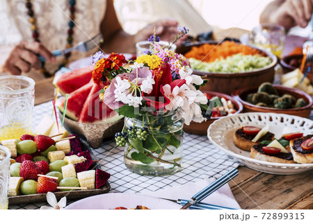 Close up of table full of food and flower decoration - colorful decorations and vegetarian lunch concept for group of people together eating and celebrating traditions 72899315
