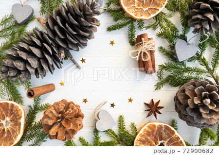 Christmas background - Christmas tree branches, pine cones, cinnamon, star anise, orange chips on a white background with space for text. Layout of a postcard, poster. 72900682