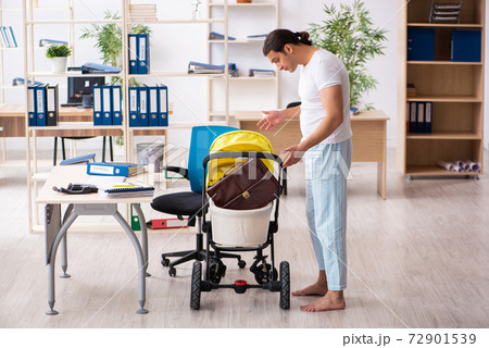 Young male employee looking after newborn at workplace 72901539