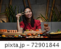 Woman is holding chopsticks with sushi opposite her eye 72901844