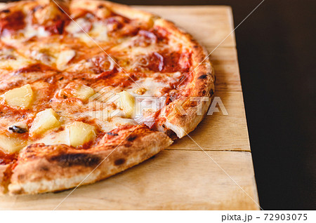 Tasty tradition Hawaiian and Salami pizza pie cooking ingredients bacon tomatoes on black table in original restaurant background. Top view of hot pepperoni pizza. Copy space. Wood-fired oven pizza 72903075