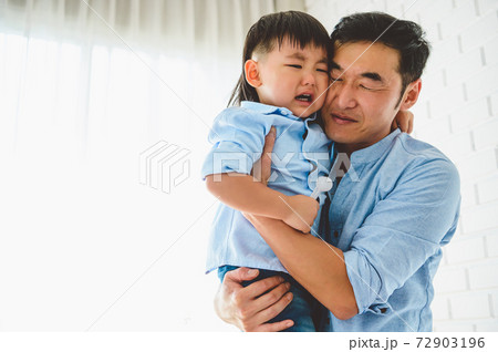 Asian Japanese father carrying and consoling his crying son in bedroom at his home with window and white curtain background. People lifestyle health. Quarantine in Covid-19 or Coranavirus epidemic 72903196