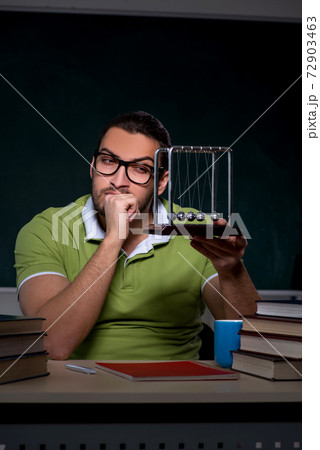 Young male student physicist working hard at night time 72903463