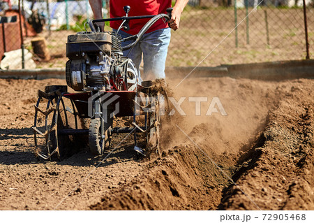 Man working in the garden with Garden Tiller. 72905468