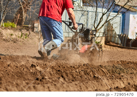 Gardener cultivate ground soil with tiller tractor or rototiller, cutivator 72905470