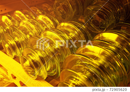On the shelf are gold-colored glass insulators for high-voltage electric poles. On the shelf are gold-colored glass insulators for high-voltage electric poles. 72905620