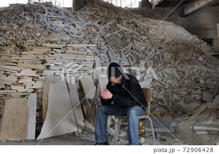 man and pile of broken marble 72906428