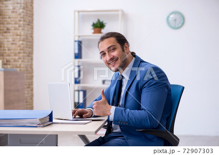 Young male employee working at workplace 72907303