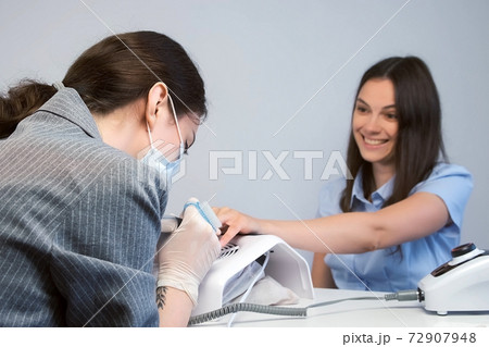 Smiling woman client on hardware manicure in beauty salon talking with master. Smiling woman client on hardware manicure in beauty salon talking with master. 72907948