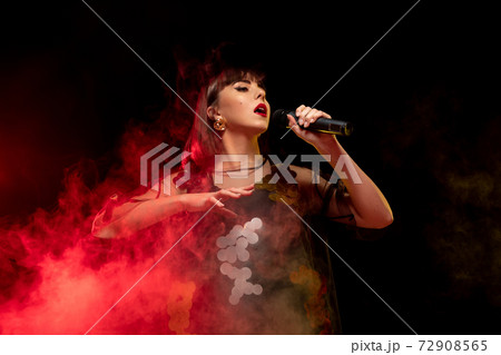 Caucasian female singer portrait isolated on dark studio background in neon light Caucasian female singer portrait isolated on dark studio background in neon light 72908565