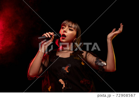 Caucasian female singer portrait isolated on dark studio background in neon light 72908567